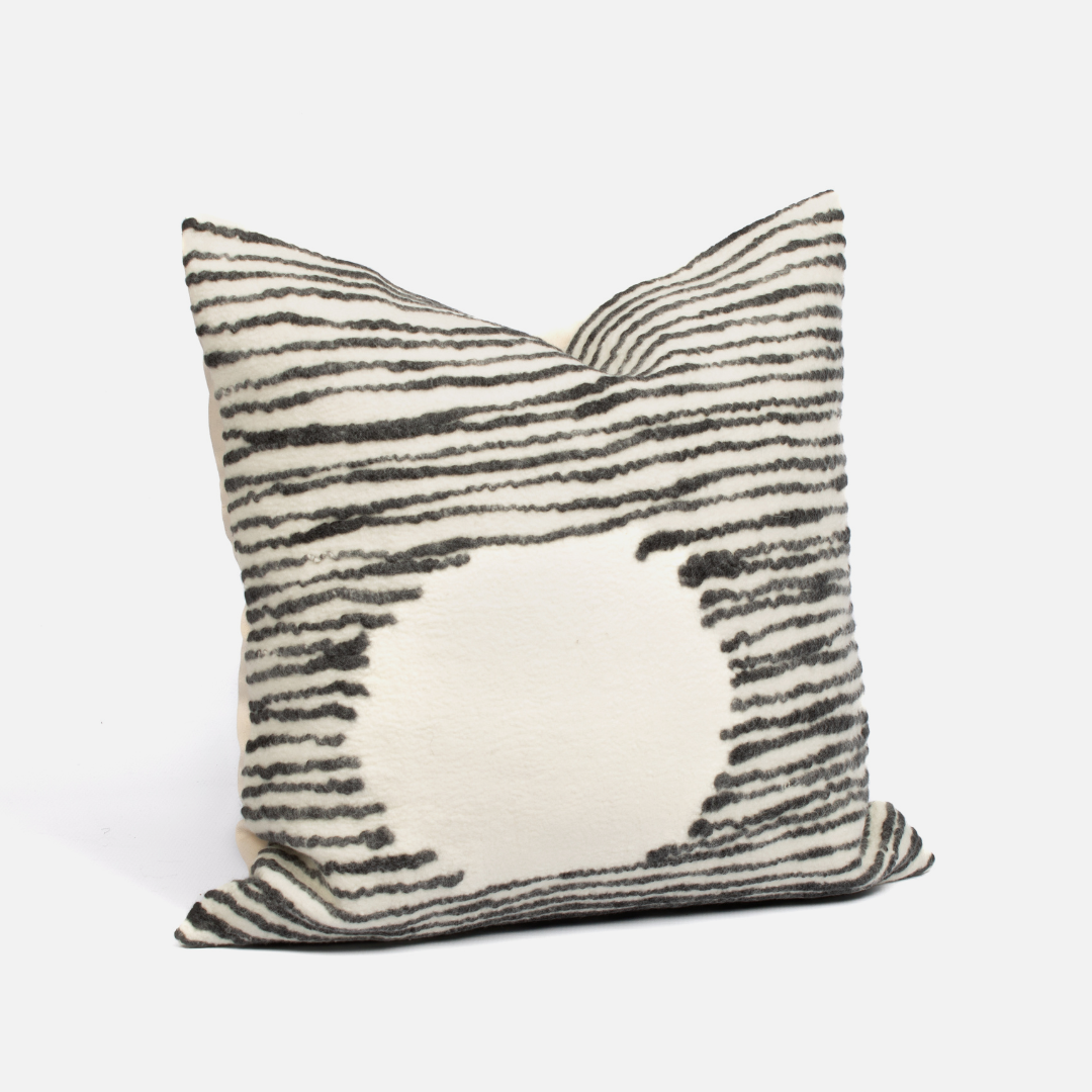 A square-shaped cushion cover with a geometric pattern featuring black and white stripes and a solid beige section in the center.