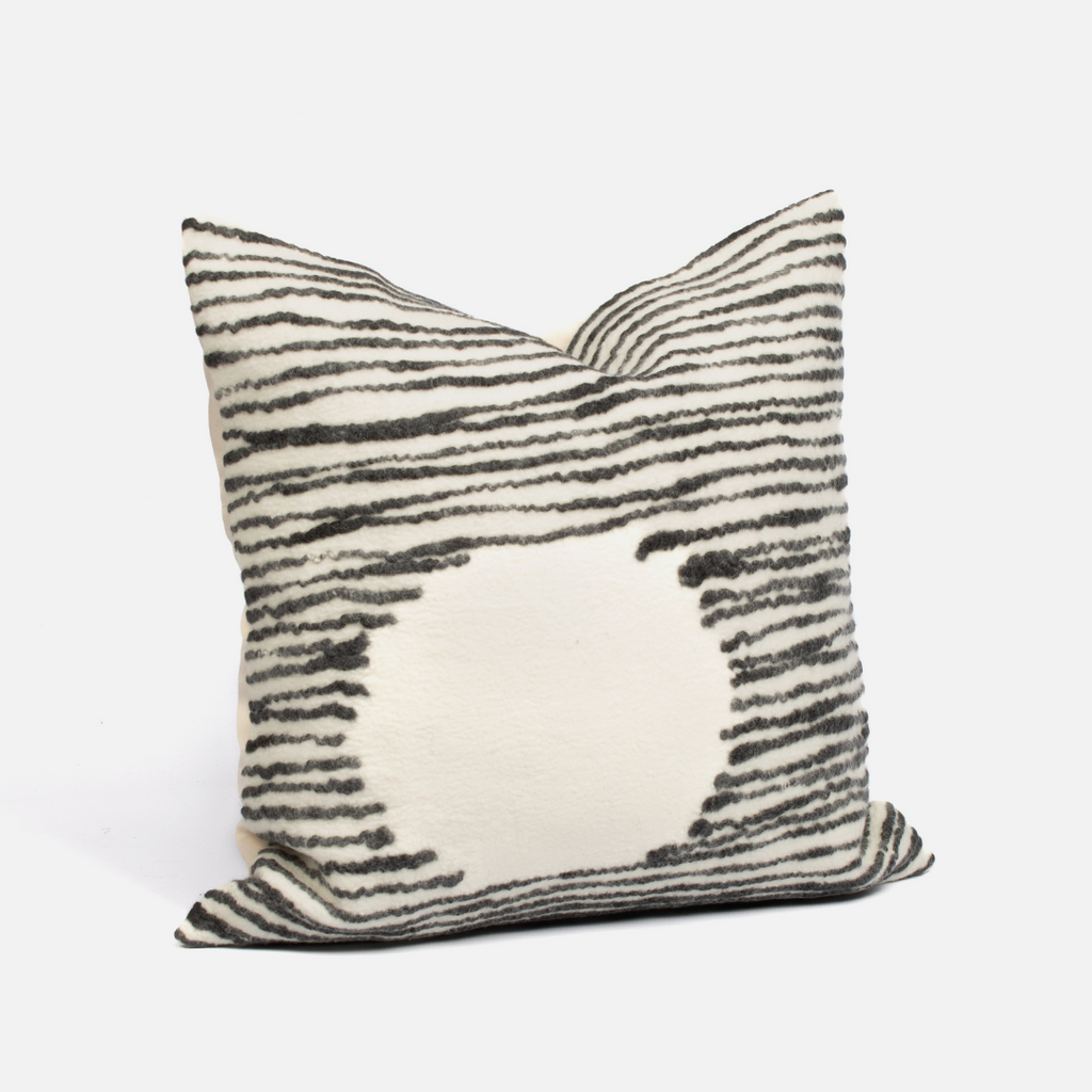 A square-shaped cushion cover with a geometric pattern featuring black and white stripes and a solid beige section in the center.