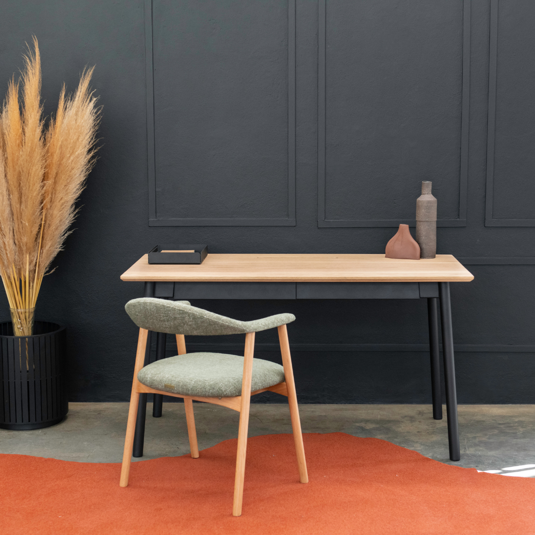 Wooden desk with chair against a dark wall with decorative elements.