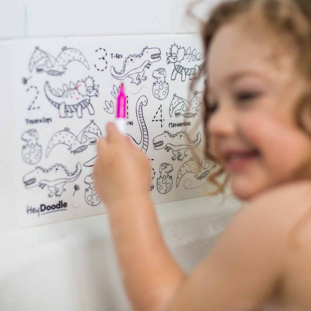 Child coloring a dinosaur-themed activity sheet with a marker on a white surface.