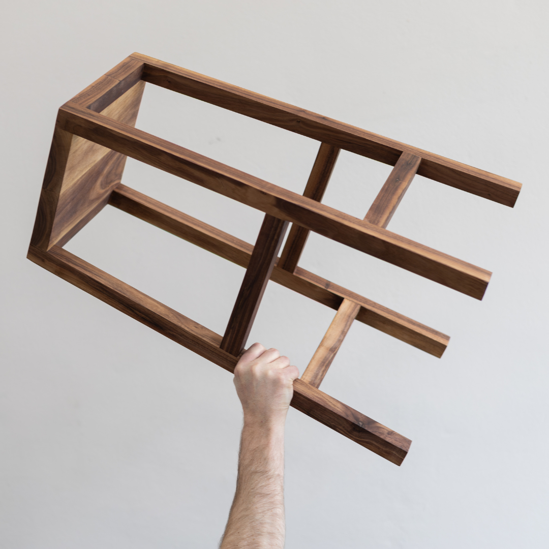 A Japandi style kitchen stool, locally made from solid Walnut being held in the air 