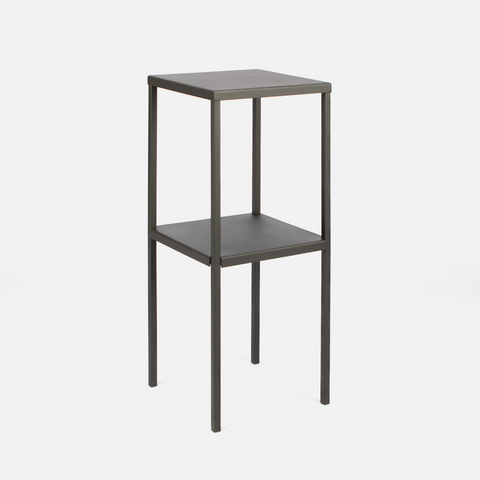 A tall, black, powder-coated steel side table with a rectangular shape and one shelf.