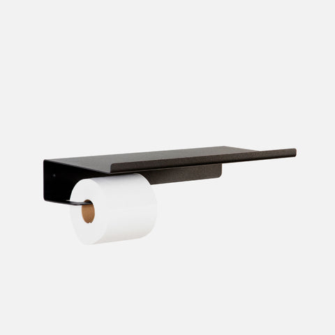 A black Nero Bathroom Shelf with a toilet roll holder, mounted on a white wall, with sufficient space for storage.
